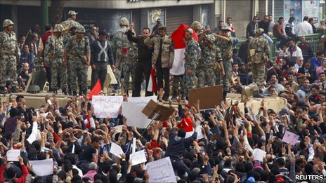 An Egyptian army officer salutes protesters from atop an army armoured personnel carrier in Tahrir square in Cairo, 29 January