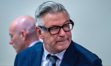 a man in a suit and glasses sits in court