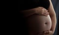 Stock photograph showing a closeup of a pregnant woman's baby bump