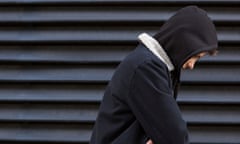 Lonely teenage boy in front of black background looking down