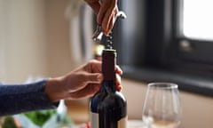 A person opening a bottle of wine with a corkscrew