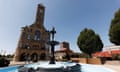 Wrought iron fountain with blue bowl, across square from limestone building.