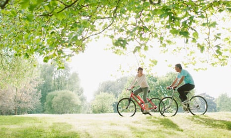 Couple riding bicycles underneath tree