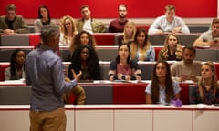 Back view of man presenting to students at a lecture theatre