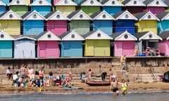 Families on the beach in front of rows of beach huts