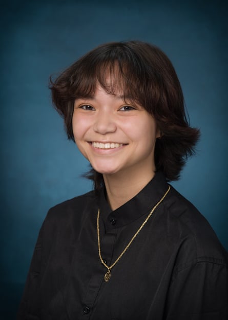 School photo of brightly smiling boy wearing black shirt and gold chain.