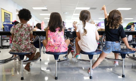 Four young schoolchildren eating in a cafeteria