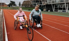 Women in wheelchair shows girl in wheelchair how to race on an athletics track