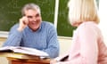 Portrait of mature male teacher speaking to female during training course, with blackboard in the background