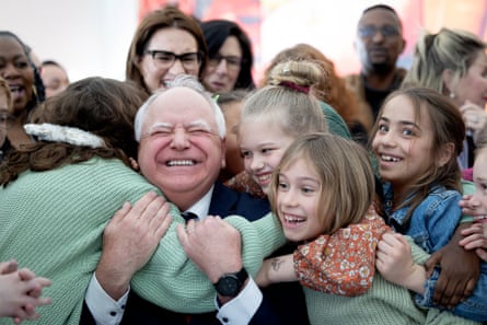 A middle-aged man is swarmed and hugged by children.