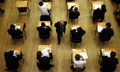 Aerial view of an invigilator walking past rows of pupils wearing school uniform sitting an exam