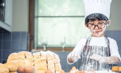 Boy wearing glasses cooking with white flour and kneading bread dough.