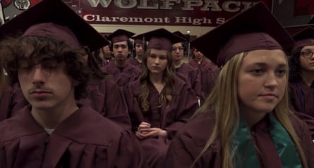 Group of teenagers in purple graduation robes and hats.