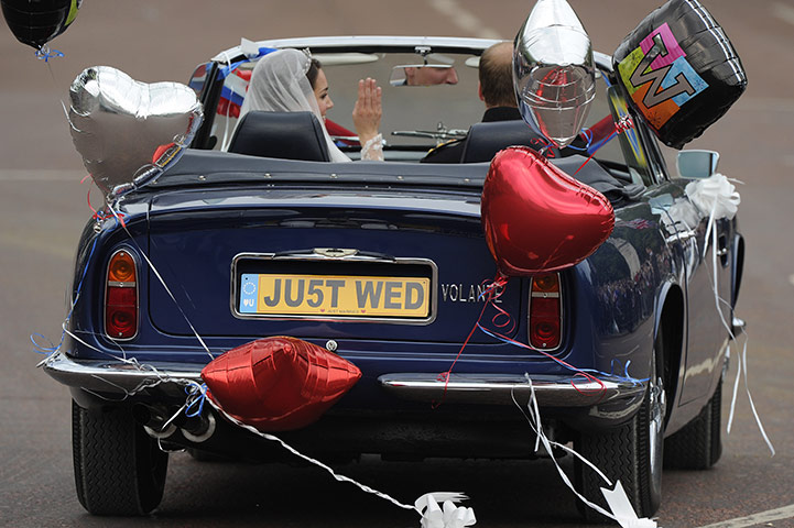 Wedding procession: The couple wave to the crowds in an open-top Aston Martin Volante