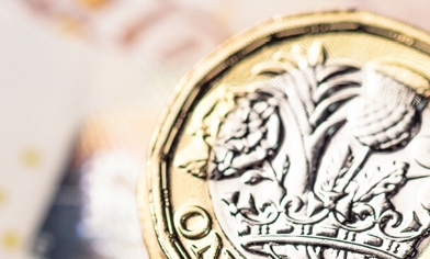 A £5 bank note placed on the left, a British one pound coin, face up on the right