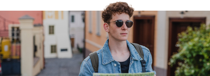 Man wearing sunglasses in a European city holding a map 