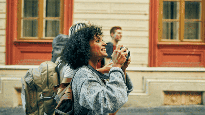 Woman wearing a backpack, smiling, looking up about to take a photo