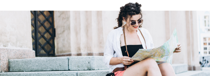 Woman in a city centre location sitting on some steps reading a map