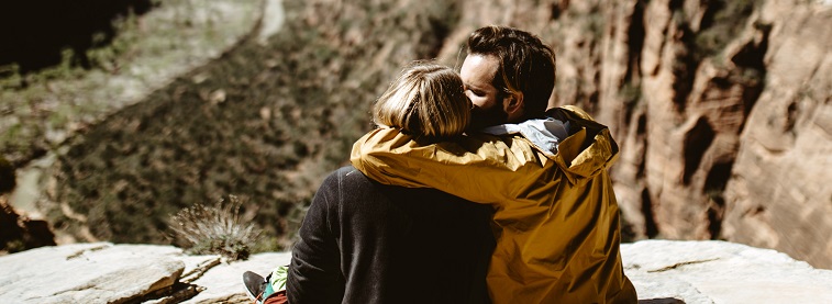 Couple sitting on rock hill, embracing