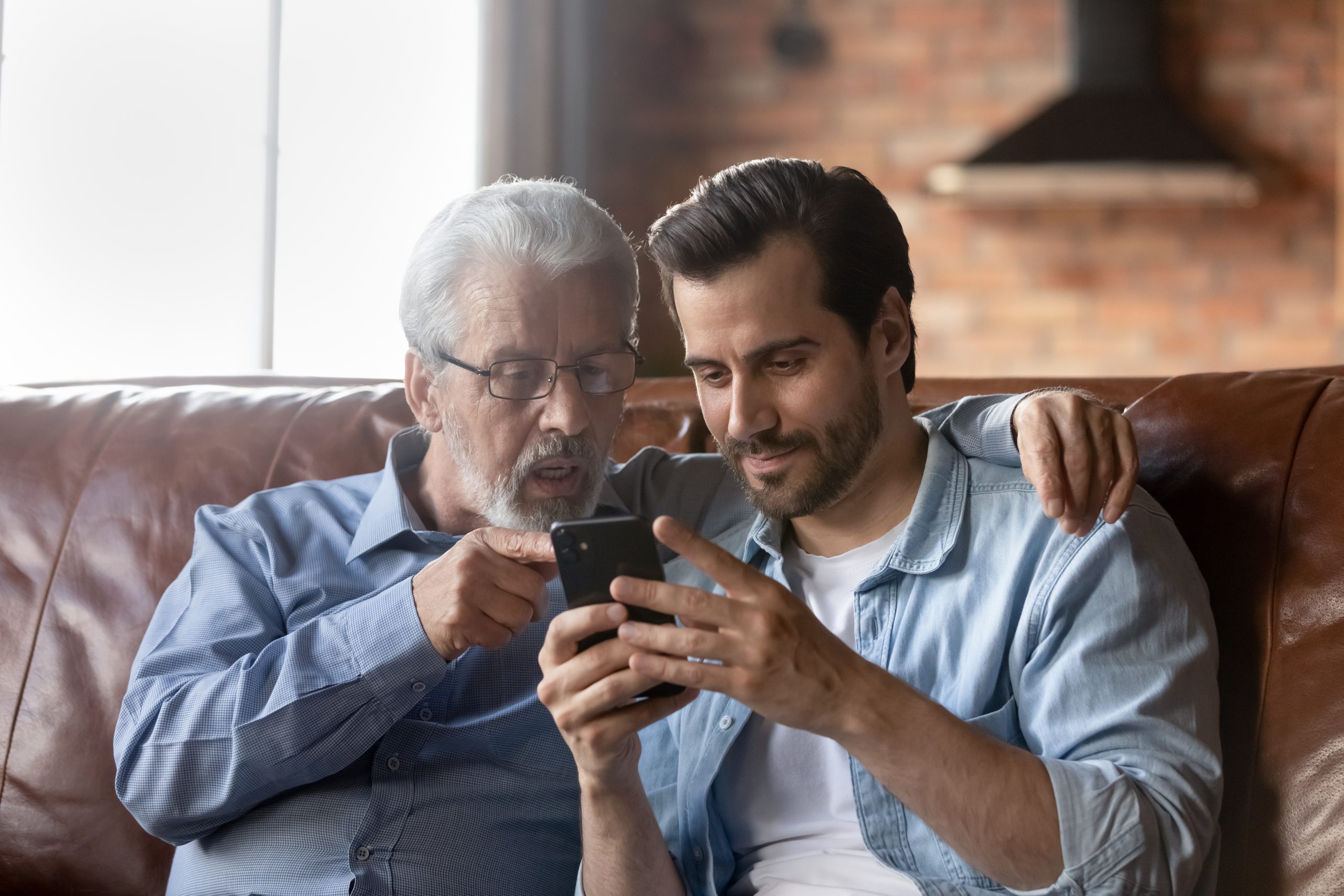 Young man helping his dad with his smartphone