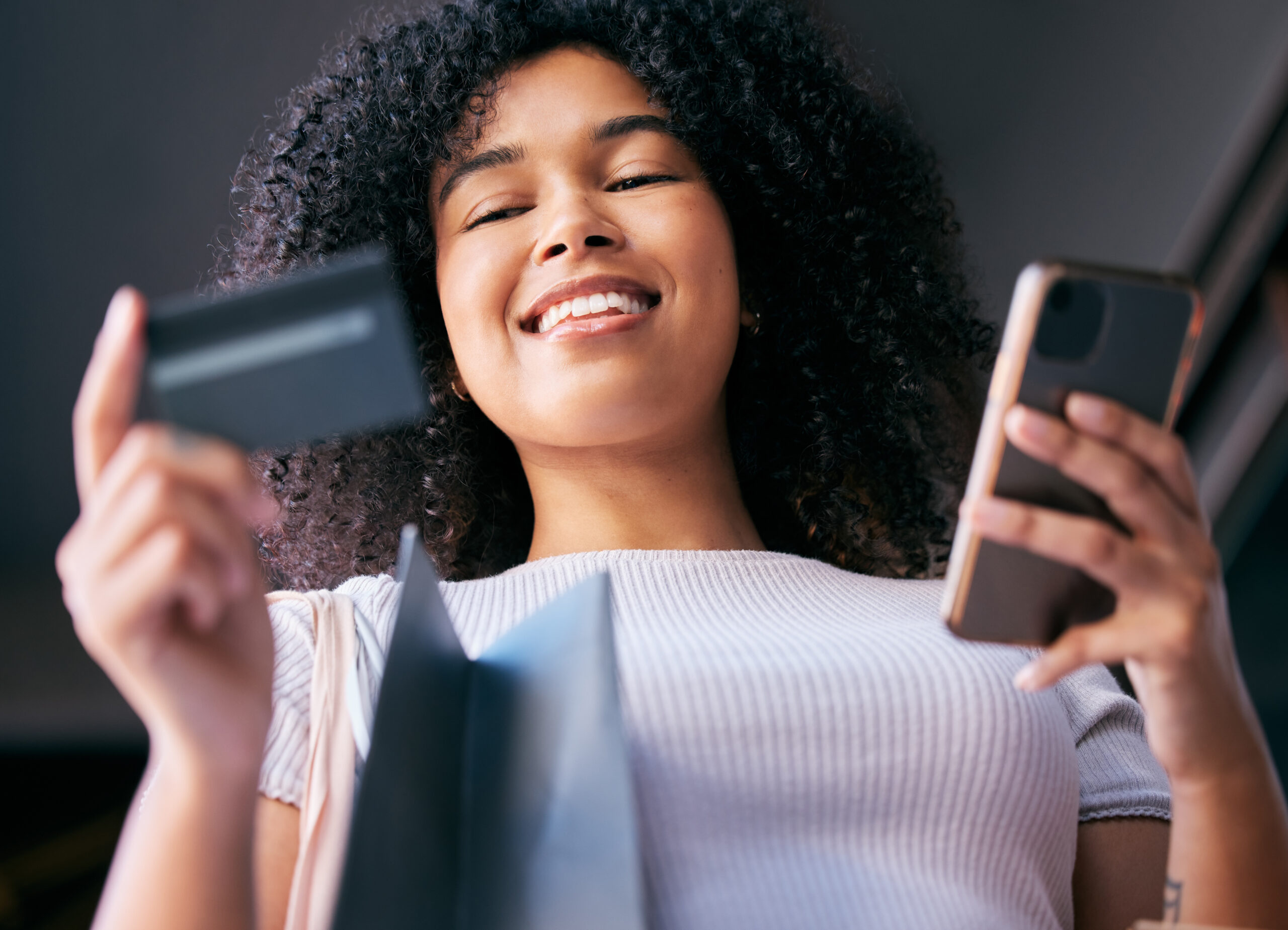 stock photo of a woman using her smartphone and her credit card simultaneously